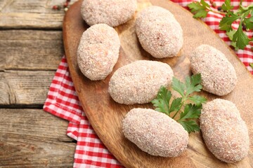 Uncooked meat patties and parsley on wooden table, above view