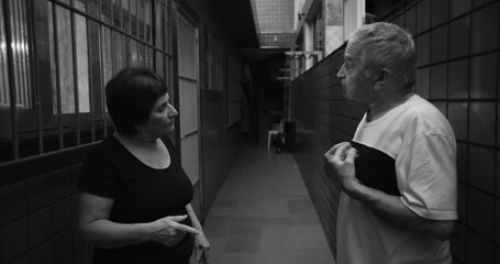 Elderly couple confronting each other in heated argument, expressive gestures and intense discussion in a hallway, black and white depiction of emotional tension - Powered by Adobe
