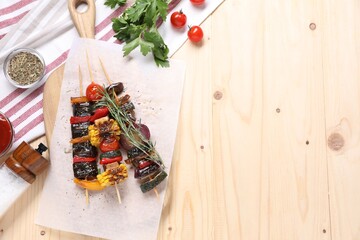 Skewers with tasty grilled vegetables served on wooden table, flat lay. Space for text