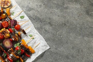 Skewers with tasty grilled vegetables served on grey table, top view. Space for text