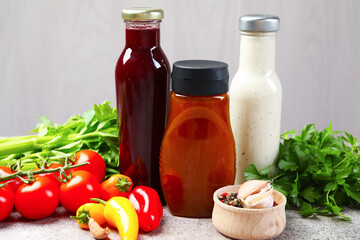 Bottles of different tasty sauces and products on grey table, closeup