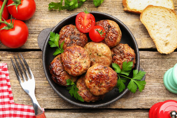 Delicious patties with parsley, tomatoes and bread served on wooden table, flat lay