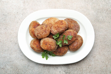 Tasty meat patties with parsley on grey table, top view