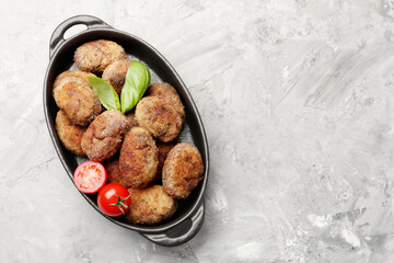 Tasty meat patties with basil and tomatoes on grey textured table, top view. Space for text