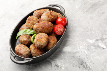 Tasty meat patties with basil and tomatoes on grey textured table. Space for text