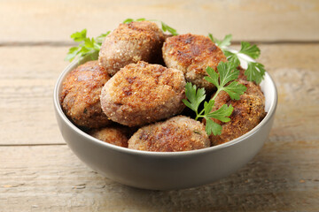 Tasty meat patties with parsley o wooden table, closeup