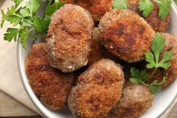Tasty meat patties with parsley o wooden table, top view