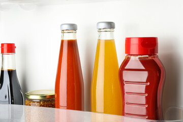 Bottles with different tasty sauces in fridge, closeup