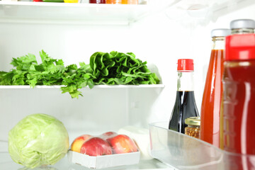 Bottles with different tasty sauces and products in fridge, closeup