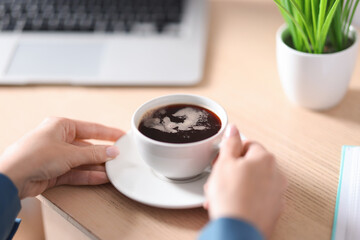 Woman having coffee break at wooden table, closeup