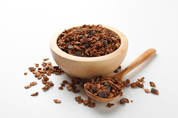 Delicious granola with chocolate chips in bowl and spoon on white background, closeup