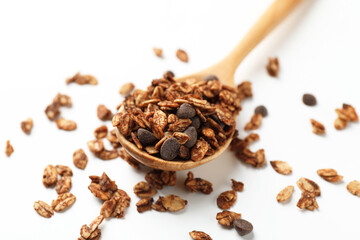 Delicious granola with chocolate chips in spoon on white background, closeup