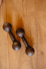 Two black dumbbells for sports lying on a wooden floor, filmed from above