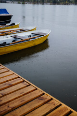 Wooden pier with swimming equipment near the lake in the rain, close-up