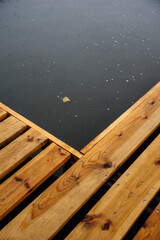 Wooden pier with swimming equipment near the lake in the rain, close-up