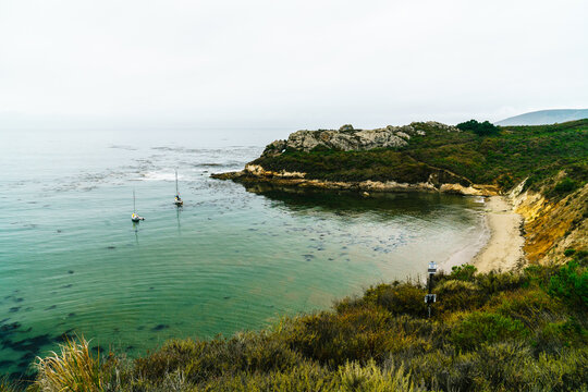 Secluded Coastal Cove with Sailboats and Rocky Shoreline