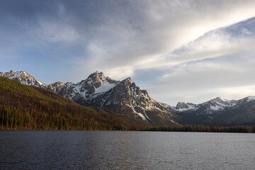 Sunset at stanley lake in the sawtooth mountain range in idaho with beautiful clouds and snow capped mountain top during the fall with some trees burned in a recent forest fire