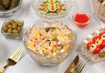 Festive Christmas and New Year's dishes on an elegant table. Festive Olivier salad, radish and cucumber salad, olives, red caviar, pickles, and glasses of champagne. Healthy lifestyle concept