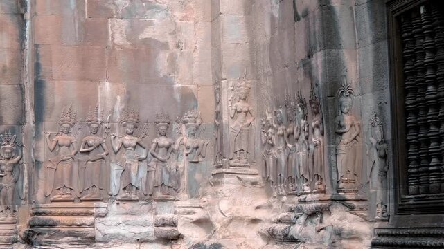 Dozens of beautiful divine dancers - Apsaras carved on the stone walls of Angkor Wat, Cambodia. Shot in motion