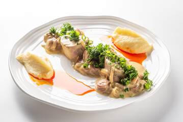 gourmet dish featuring sliced chicken or pork with a creamy mushroom sauce and fresh herbs, served with a side of mashed potatoes on a white plate.