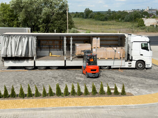 Forklift unloading cargo pallets from truck trailer