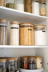 Neatly organized labeled food pantry in a home kitchen with spices grains flour rice sugar nuts