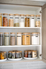 Neatly organized labeled food pantry in a home kitchen with spices grains flour rice sugar nuts
