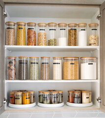 Neatly organized labeled food pantry in a home kitchen with spices grains flour rice sugar nuts