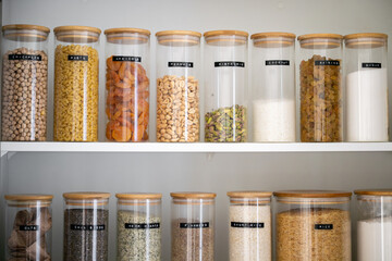Neatly organized labeled food pantry in a home kitchen with spices grains flour rice sugar nuts