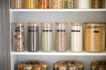 Neatly organized labeled food pantry in a home kitchen with spices grains flour rice sugar nuts