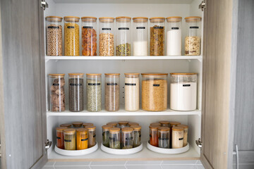 Neatly organized labeled food pantry in a home kitchen with spices grains flour rice sugar nuts