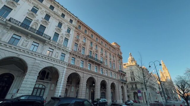 Detailed close-up of an ornate Art Nouveau residential in Vienna. The Secession-style building features sculpted details, curved balconies, and intricate stucco work under a blue sky.