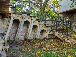 External stone staircase with arched buttresses and a decorative wrought iron railing, set against...