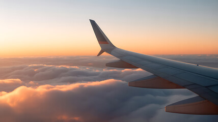 Obraz premium Airplane wing above soft clouds at sunset with orange and blue sky above clouds orange sky
