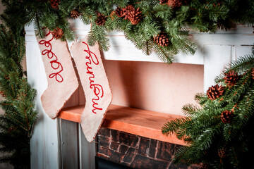 Christmas sock for gifts hanging on a fireplace decorated with a pine garland with cones. Vintage. Christmas background. New Year's Eve. Winter holidays. Gifts. Santa.