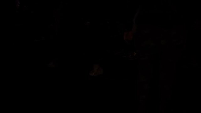 Dimly Lit Scene with People Standing and dacing Over Colorful Streamers on Dark Floor