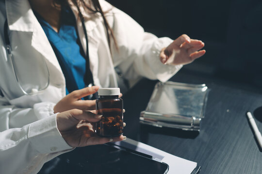 Two doctors and a female nurse meet at a table in the hospital, collaborating on medical tasks using laptops and computers - Powered by Adobe