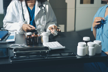 Female doctor holding a medicine bottle is checking the quality of medicine for any side effects the patient or not and recording patient information at the hospital. medical and health care concept