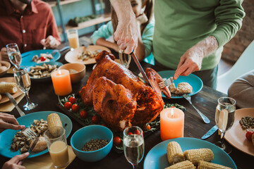 Funny warm family feast around a roasted turkey as relatives gather for a cozy autumn thanksgiving dinner around a festive table