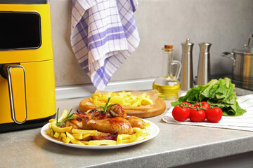 Grilled chicken drumsticks with french fries, ingredients and air fryer on grey countertop, closeup