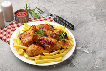 Grilled chicken drumsticks served with french fries and spices on grey table, closeup. Space for text