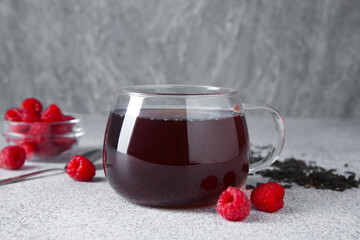 Delicious tea, raspberries and brew served on light table, closeup