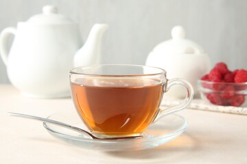 Delicious tea and raspberries on white table, closeup