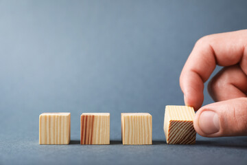 Man with wooden cubes on grey background, closeup. Space for text