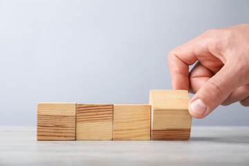 Man with wooden cubes on light background, closeup. Space for text