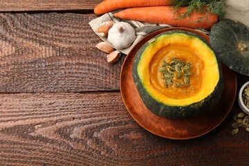 Tasty pumpkin cream soup with seeds and thyme served in pumpkin on wooden table, flat lay. Space for text