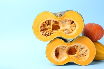 Whole and cut pumpkins on light blue background, closeup with space for text. Gourd family