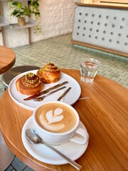 a cup of cappuccino with tasty pastry on the wooden table