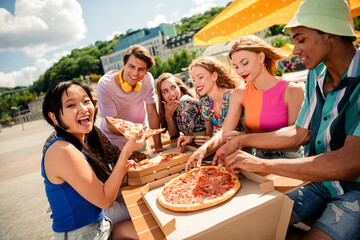 Group of friends enjoying pizza together outdoors on a sunny day, celebrating friendship and creating joyful summer memories
