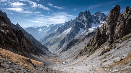 Majestic snow capped mountain range under a vibrant blue sky with dramatic clouds, showcasing rugged terrain and vast natural beauty.